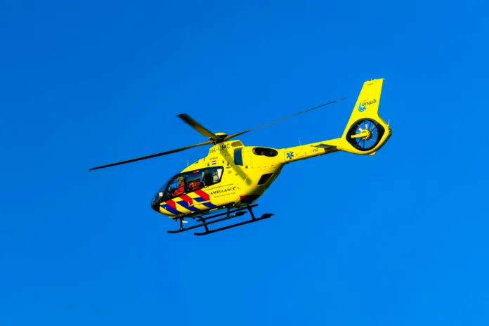 Een trauma helikopter in de lucht, van de zijkant gefotografeerd met een blauwe lucht op de achtergrond
