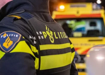 Politie agent logo op rug donker met ambulance op de achtergrond